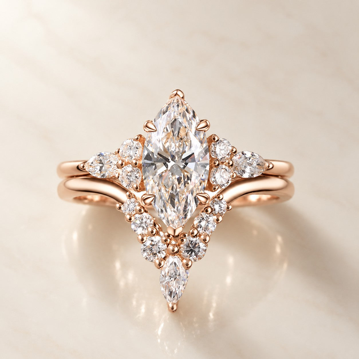 Angled view of a rose gold marquise bridal ring set on an ivory reflective surface