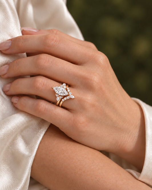 Rose gold marquise bridal ring set worn on the ring finger beside ivory satin